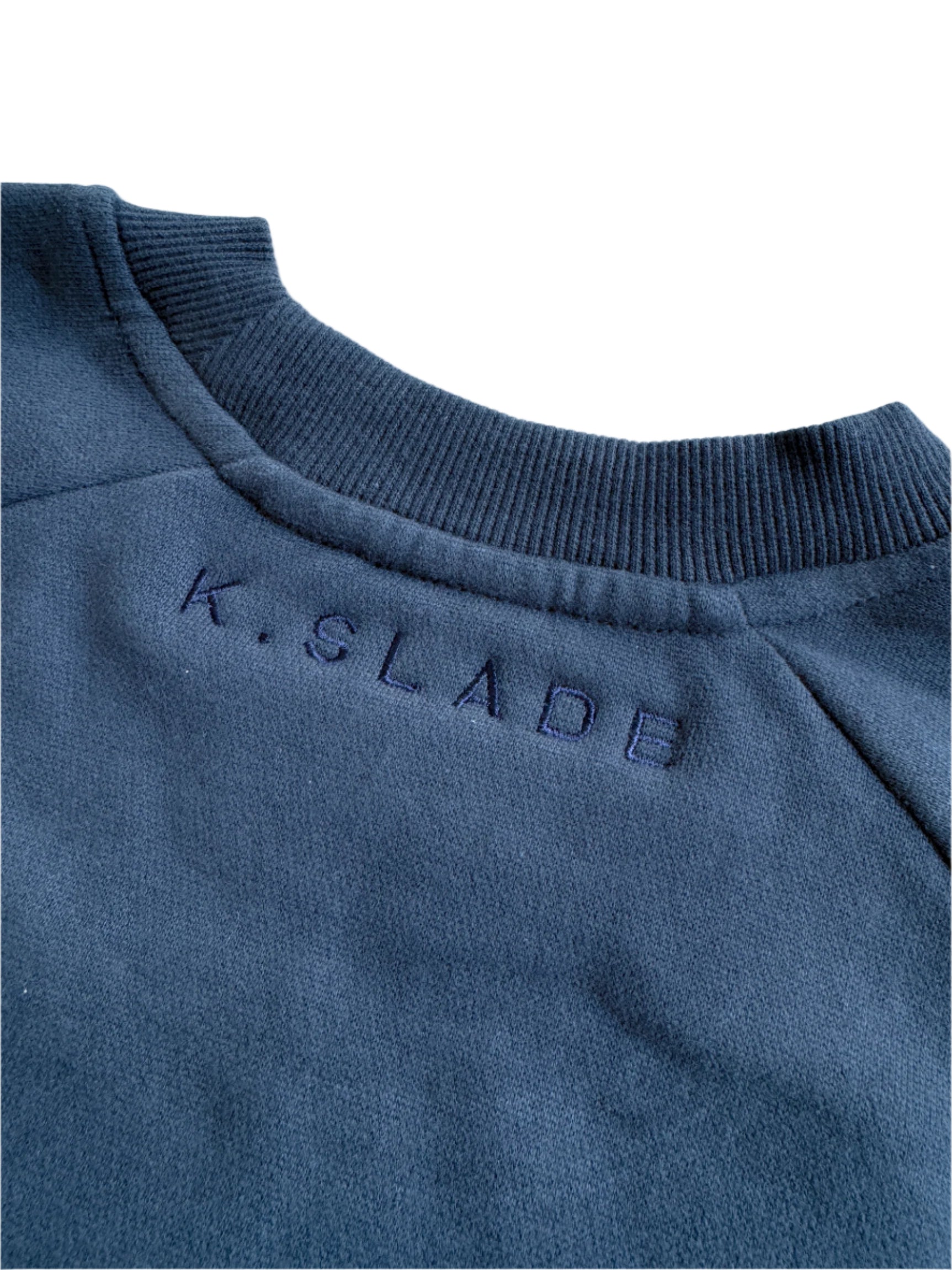 Close-up of a blue sweatshirt with 'K. SLADE' branding on a light blue background