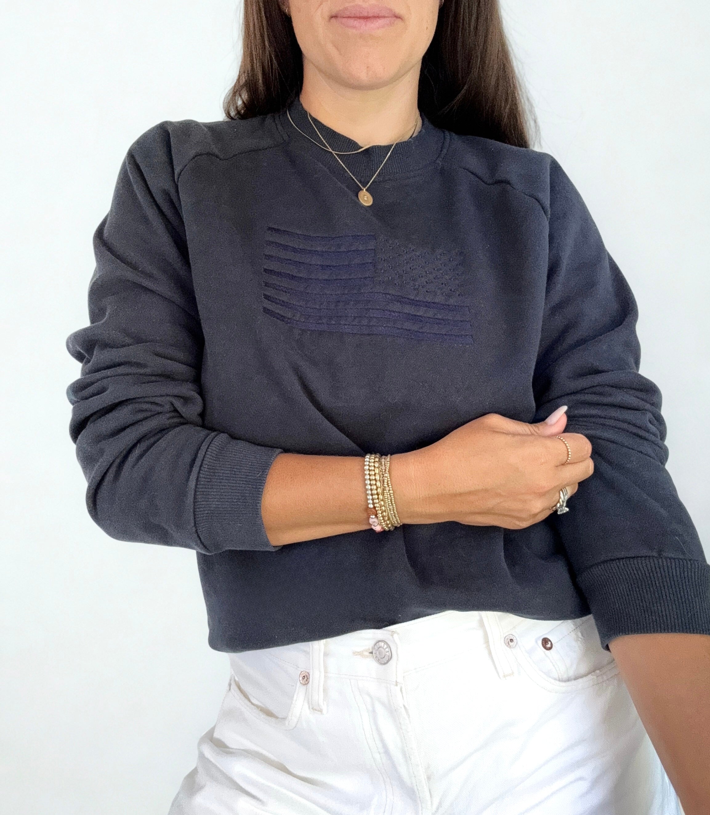 Person wearing a dark blue sweater and white pants on a plain background