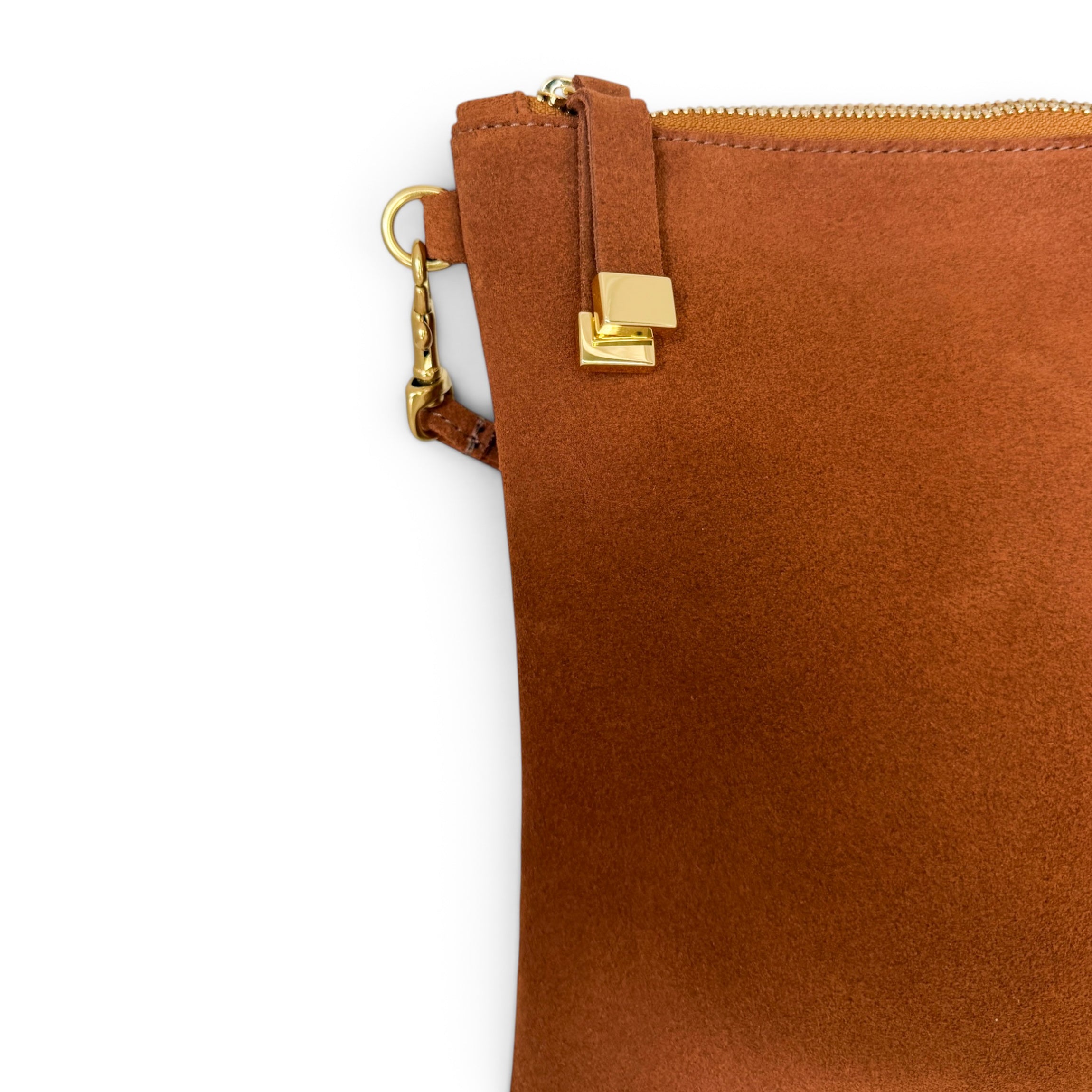 Close-up of a warm brown suede pouch with gold-tone hardware, including a zipper, strap tab, and clasp, on a plain white background.