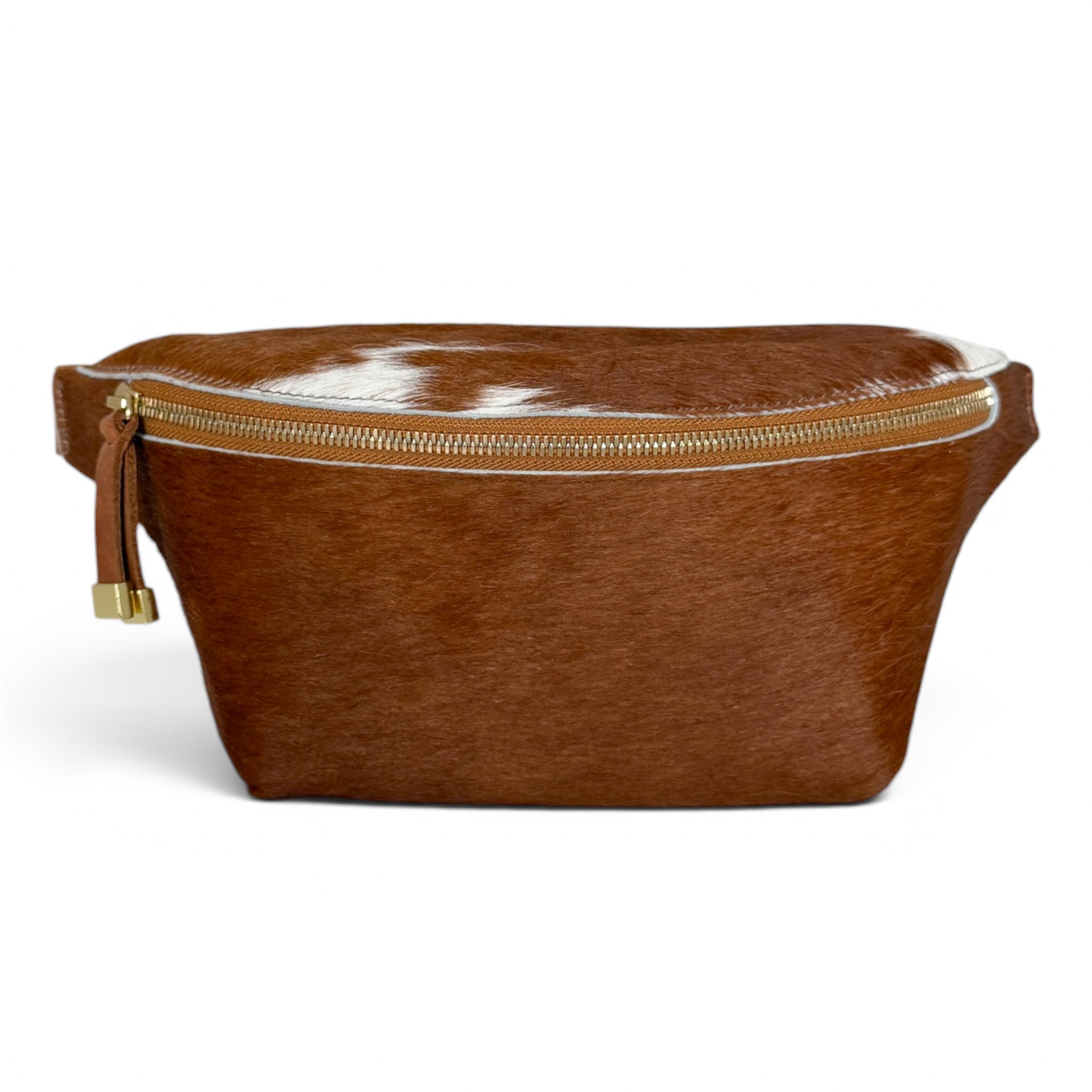 A brown cowhide belt bag with a gold zipper and a small leather tassel pull, shown on a plain white background.